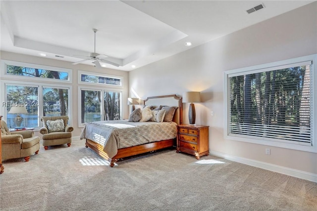 bedroom with ceiling fan, a tray ceiling, and light carpet