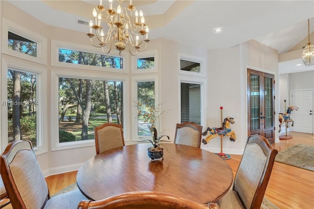 dining room featuring light wood-type flooring, a wealth of natural light, and an inviting chandelier