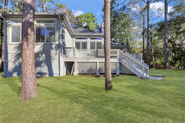 back of property with a wooden deck and a lawn