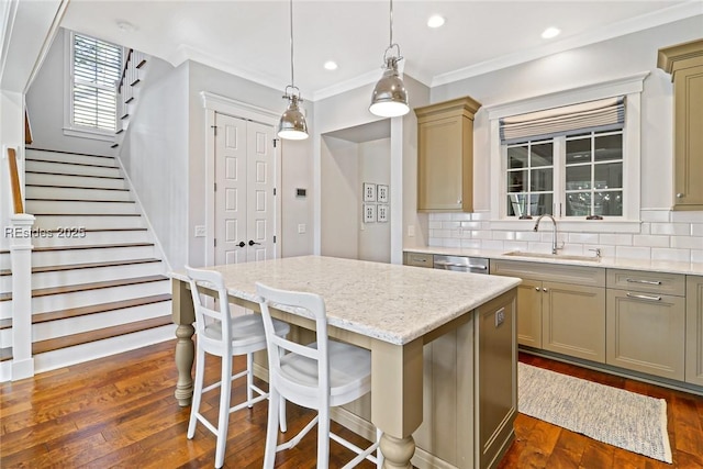 kitchen featuring sink, decorative light fixtures, dishwasher, a kitchen island, and backsplash