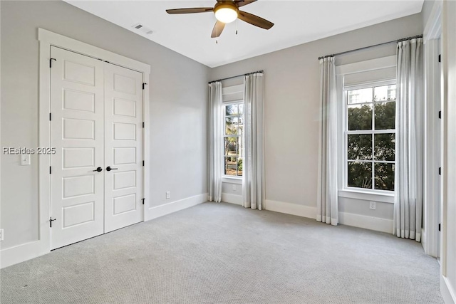 unfurnished bedroom featuring light carpet, a closet, and ceiling fan