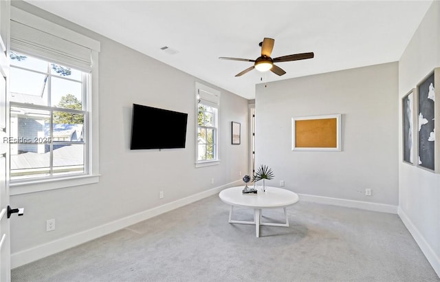 living area featuring light colored carpet and ceiling fan