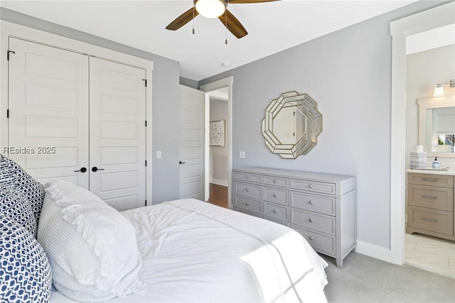 bedroom featuring ensuite bath, light carpet, ceiling fan, and a closet