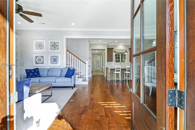 living room with dark wood-type flooring, ceiling fan, and crown molding