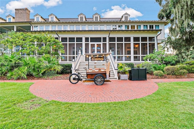 rear view of property featuring a yard and a sunroom