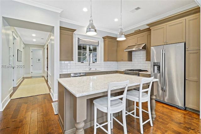 kitchen with pendant lighting, sink, appliances with stainless steel finishes, a center island, and decorative backsplash