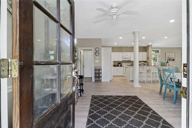 living room featuring decorative columns, ceiling fan, and light wood-type flooring