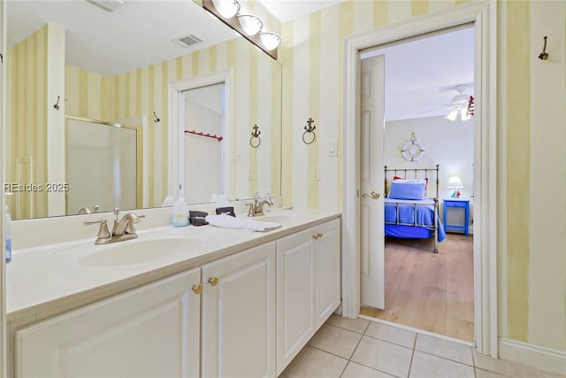 bathroom with ceiling fan, vanity, a shower with door, and tile patterned flooring