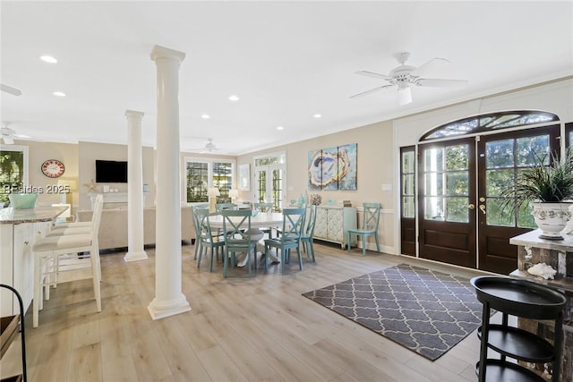 dining room featuring ornate columns, ceiling fan, light wood-type flooring, and french doors