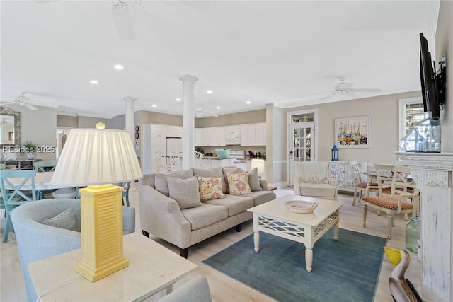 living room with hardwood / wood-style flooring, ceiling fan, and ornate columns