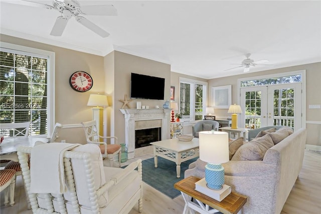 living room with french doors, ornamental molding, a wealth of natural light, and light wood-type flooring