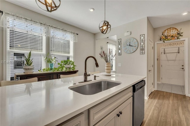 kitchen featuring pendant lighting, sink, stainless steel dishwasher, and light hardwood / wood-style floors