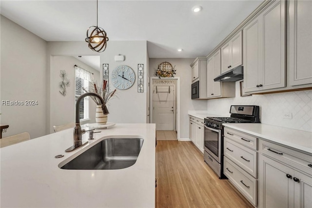 kitchen with pendant lighting, sink, black microwave, light hardwood / wood-style floors, and gas stove