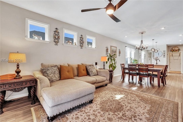 living room with hardwood / wood-style flooring and ceiling fan with notable chandelier