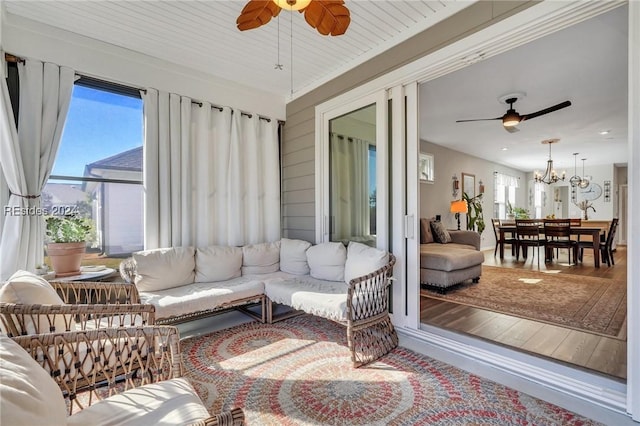 sunroom featuring plenty of natural light, ceiling fan with notable chandelier, and wooden ceiling