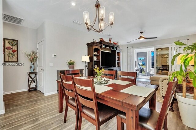 dining space featuring ceiling fan with notable chandelier and wood-type flooring