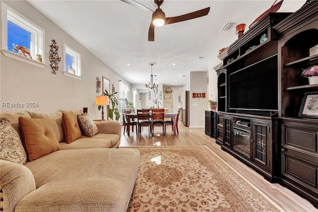 living room with ceiling fan with notable chandelier and light hardwood / wood-style floors