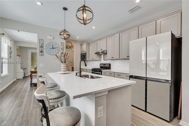 kitchen featuring gray cabinets, appliances with stainless steel finishes, pendant lighting, sink, and a center island with sink