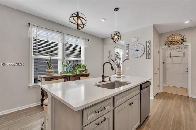 kitchen with an island with sink, sink, stainless steel dishwasher, and light hardwood / wood-style floors