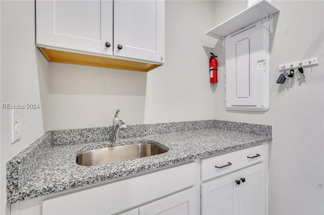 kitchen featuring light stone countertops, sink, and white cabinets