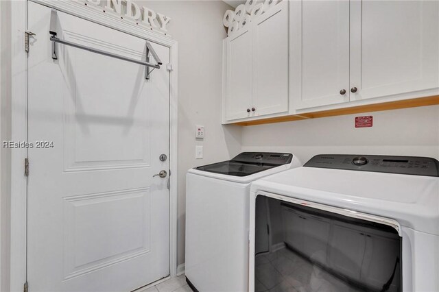 laundry room with light tile patterned flooring, cabinets, and washer and dryer