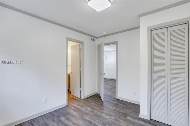 unfurnished bedroom with crown molding, a closet, and hardwood / wood-style flooring