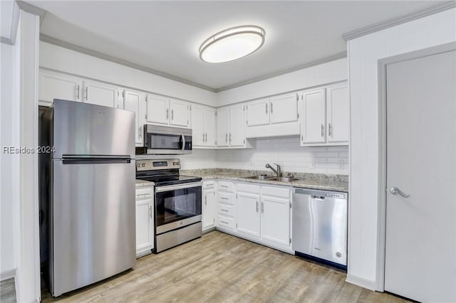 kitchen with appliances with stainless steel finishes, sink, white cabinets, light hardwood / wood-style floors, and crown molding