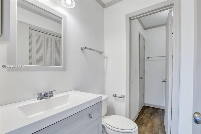 bathroom featuring hardwood / wood-style flooring, ornamental molding, toilet, and vanity