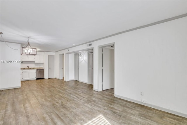 unfurnished living room featuring crown molding, light hardwood / wood-style floors, sink, and a notable chandelier