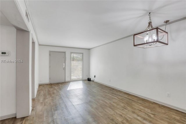 spare room featuring crown molding, a chandelier, and hardwood / wood-style flooring