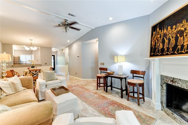 living room featuring ceiling fan with notable chandelier, a premium fireplace, and vaulted ceiling