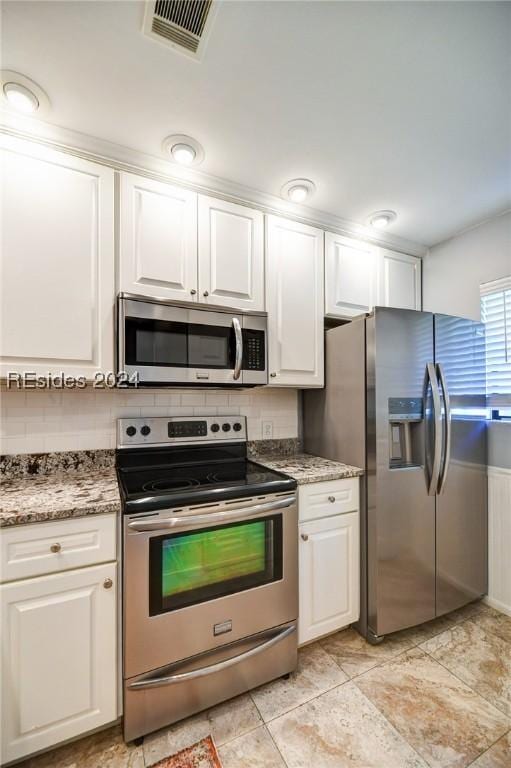 kitchen featuring tasteful backsplash, stainless steel appliances, stone countertops, and white cabinets