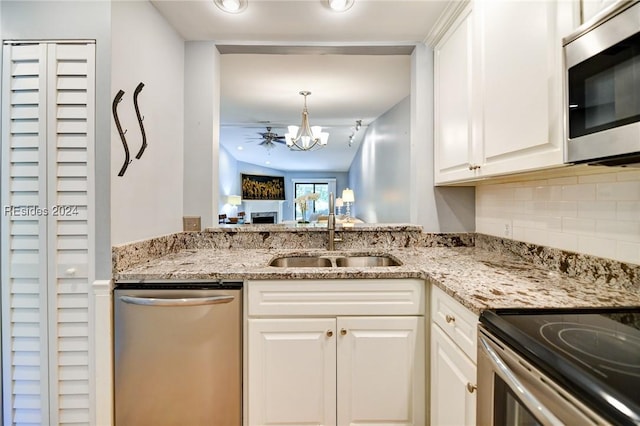 kitchen with light stone countertops, white cabinetry, appliances with stainless steel finishes, and sink