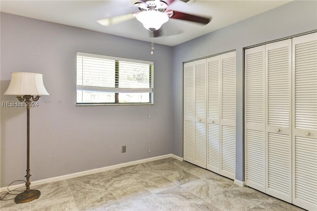 unfurnished bedroom featuring ceiling fan and two closets