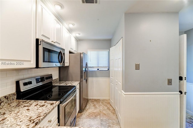 kitchen with backsplash, stainless steel appliances, light stone counters, white cabinets, and light tile patterned flooring