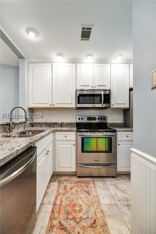 kitchen with white cabinetry, sink, light stone counters, and appliances with stainless steel finishes