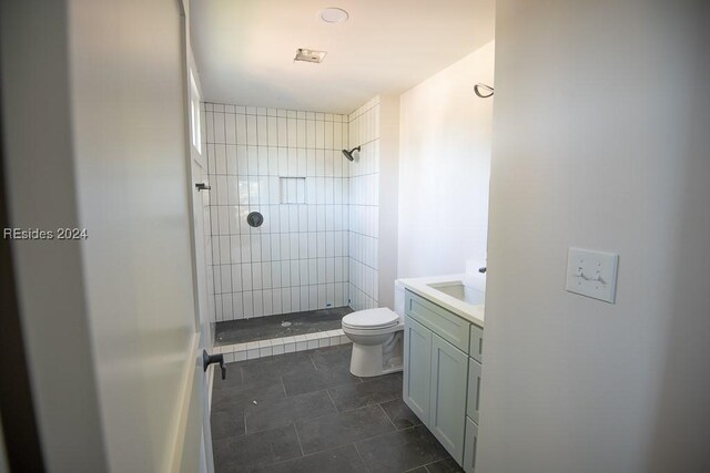 bathroom featuring vanity, tile patterned floors, toilet, and tiled shower