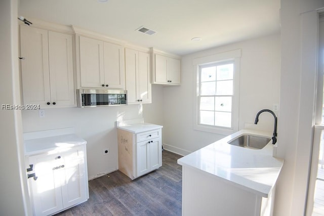 kitchen featuring a kitchen island with sink, sink, dark wood-type flooring, and white cabinets