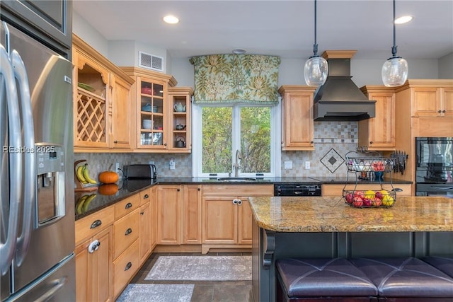 kitchen with tasteful backsplash, dark stone countertops, hanging light fixtures, black appliances, and custom range hood