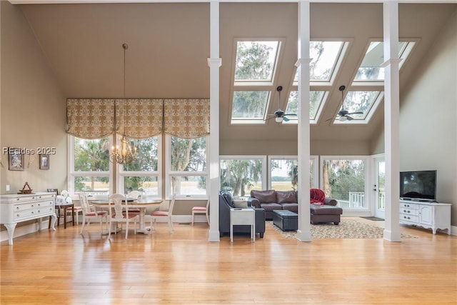 living room featuring a towering ceiling, plenty of natural light, a skylight, and light wood-type flooring