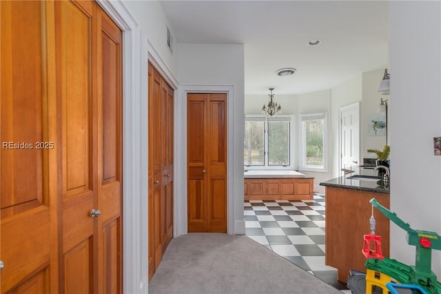 corridor featuring an inviting chandelier and sink