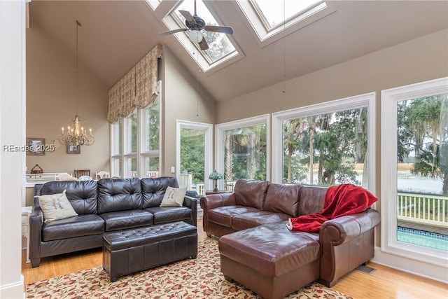 sunroom featuring ceiling fan with notable chandelier and lofted ceiling with skylight