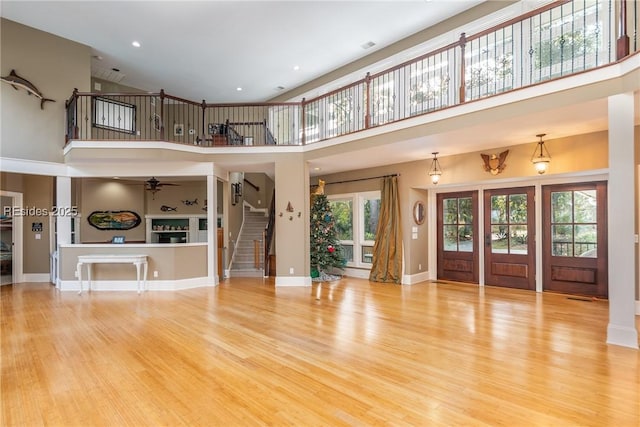 unfurnished living room featuring a towering ceiling, a wealth of natural light, and light wood-type flooring