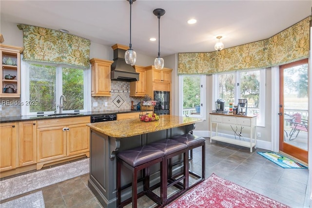 kitchen featuring sink, a kitchen breakfast bar, light stone counters, custom range hood, and a kitchen island