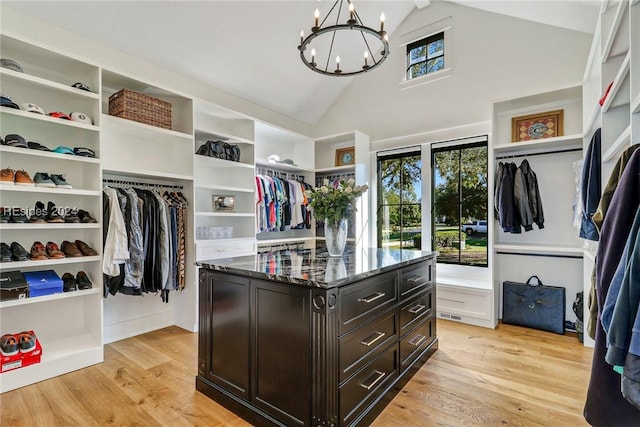 walk in closet with a notable chandelier, lofted ceiling, and light wood-type flooring