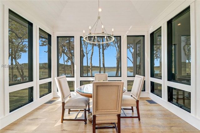 sunroom featuring a water view and an inviting chandelier