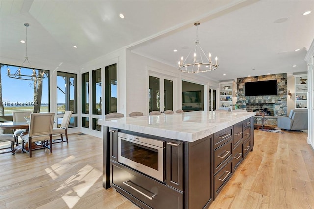 kitchen featuring stainless steel microwave, built in features, a chandelier, and decorative light fixtures