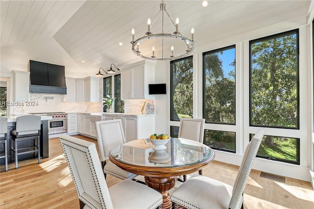 dining area featuring lofted ceiling, sink, a chandelier, wood ceiling, and light hardwood / wood-style flooring