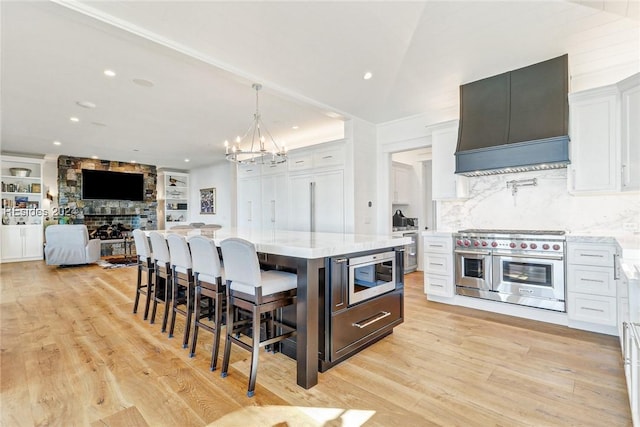 kitchen with a kitchen island, white cabinetry, a kitchen breakfast bar, custom exhaust hood, and stainless steel appliances