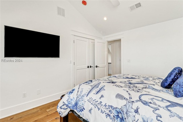 bedroom featuring wood-type flooring, vaulted ceiling, and a closet